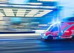 A red ambulance with sirens blaring rushing down a street in a blur. Photo by Camilo Jimenez via Unsplash.