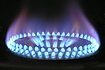 A gas stovetop burns with a blue flame against a black bacground. Photo by Pixabay.
