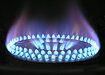 A gas stovetop burns with a blue flame against a black bacground. Photo by Pixabay.