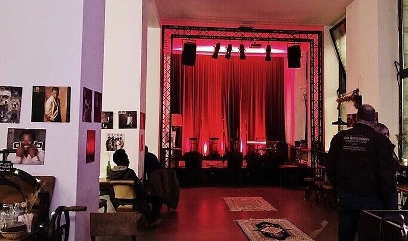 A small concert stage illumnated in red light at Prachtwerk, a live music bar and cafe in Berlin.