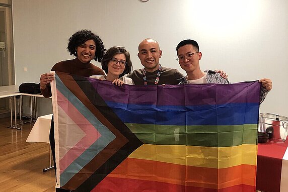 Hertie School Pride Network members hold up the rainbow flag which also incorporates the black, brown, blue, pink and white chevron (the Progress Pride Flag).