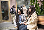 Two students sitting on a bench in front of the Hertie School's doors at Friedrichstraße